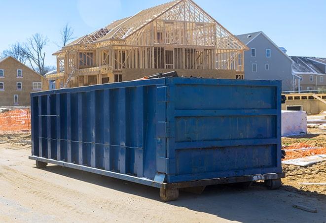 a recycling bin placed next to a residential dumpster